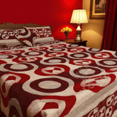 Bed with a red and white patterned comforter in a bedroom setting.